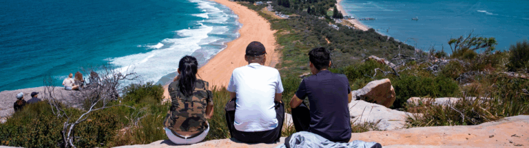 Group of 3 people looking out at beach (Adobe Stock licensed image)